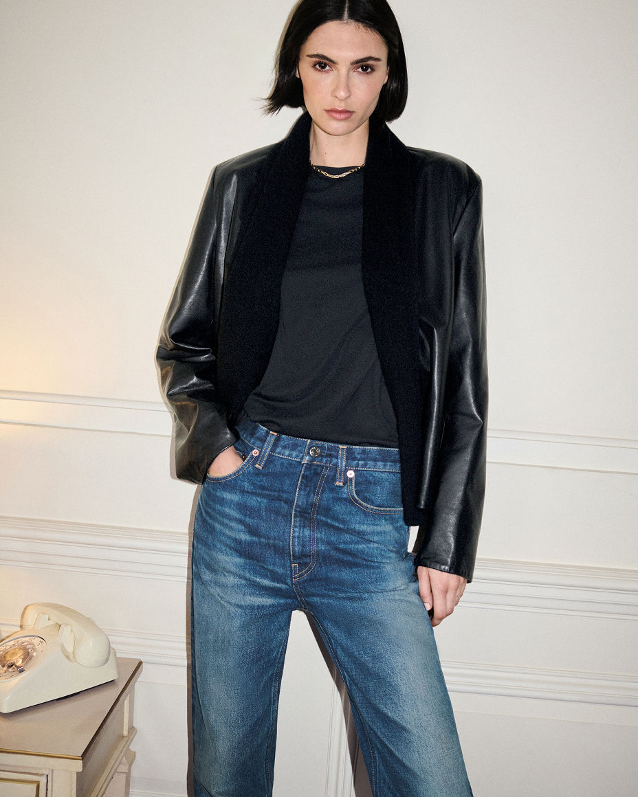 A woman in a Toteme  black jacket over a black shirt & blue jeans. The fall collections, toteme.