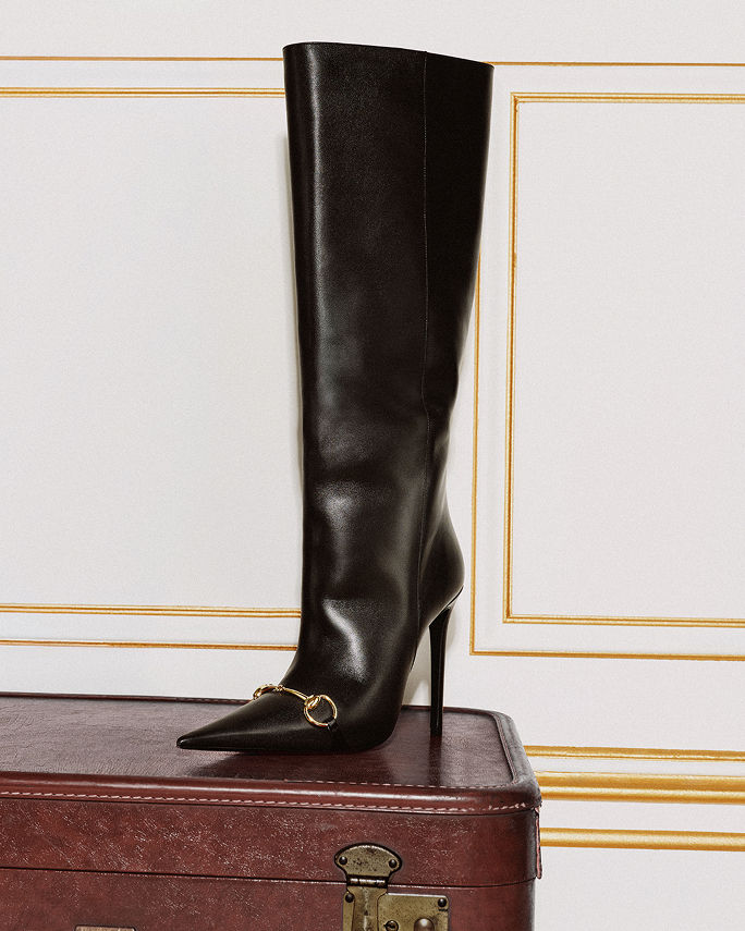 A single black tall boot with stiletto heel. Falls top 10 trends, knee high boots.