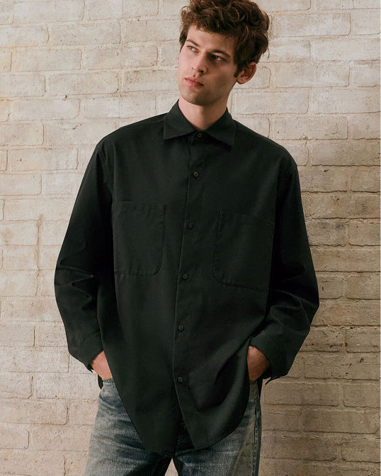 A man in an oversized black button down. Shop mens shirts.