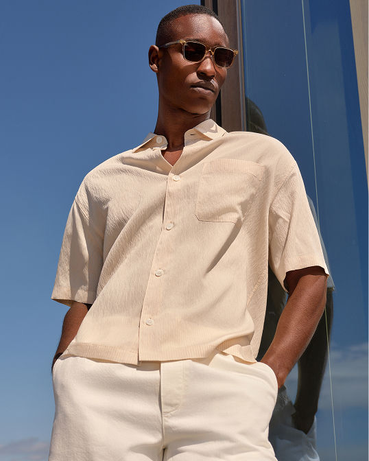 Man in tan short sleeve button up and pants.
