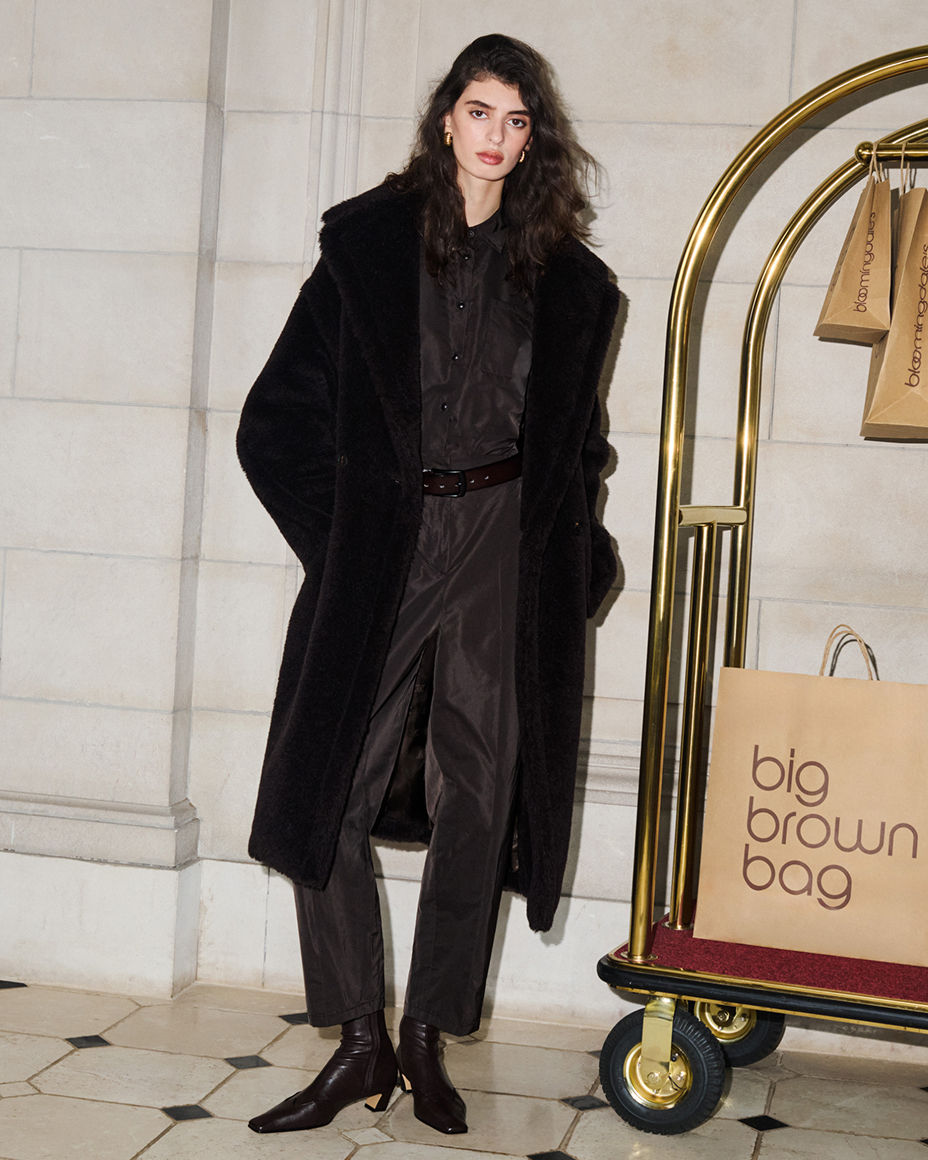 A woman in a Max Mara black long coat over black jumpsuit. The fall collections, Max Mara.