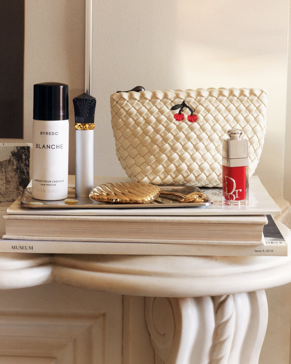 Various beauty products and a cosmetics case on top of art books.