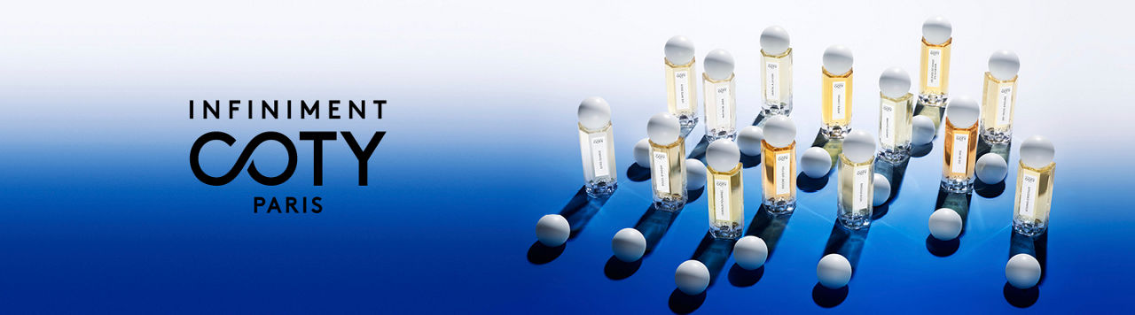 1 photo, of 14 bottles of Infiniment Coty Paris fragrance on a stark blue glassy surface, additional white bulb caps lying next to them.