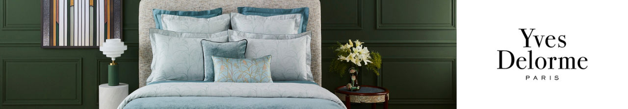 Yves Delorme Paris. A bed made up with sateen or silk Yves Delorme linens in light blue and silver.