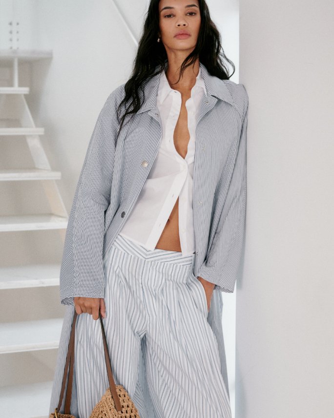 Woman in a Rag and Bone light blue striped long jacket, white top & slouchy striped pants.