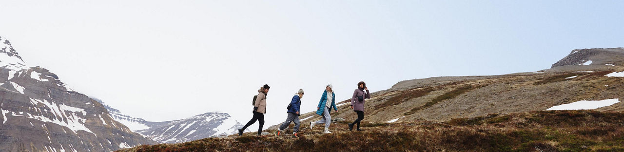 4 people in North Face puffer jackets walking along a mountain ridgeline.